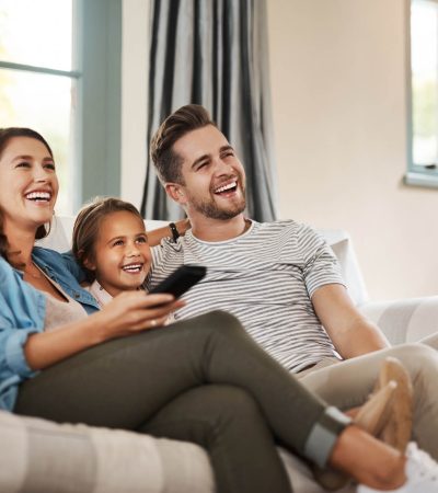 Shot of a happy young family relaxing on the sofa and watching tv together at home